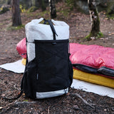Black and white backpack in a forest setting with camping gear.